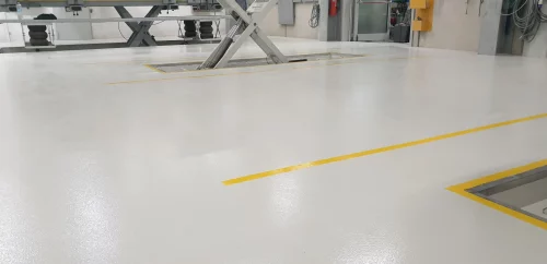 Pavimento in Resina realizzato da F-resine, di colore bianco con segnaletiche di colore giallo. Il seguente pavimento è di una carrozzeria. Pavimenti e rivestimenti in resina.